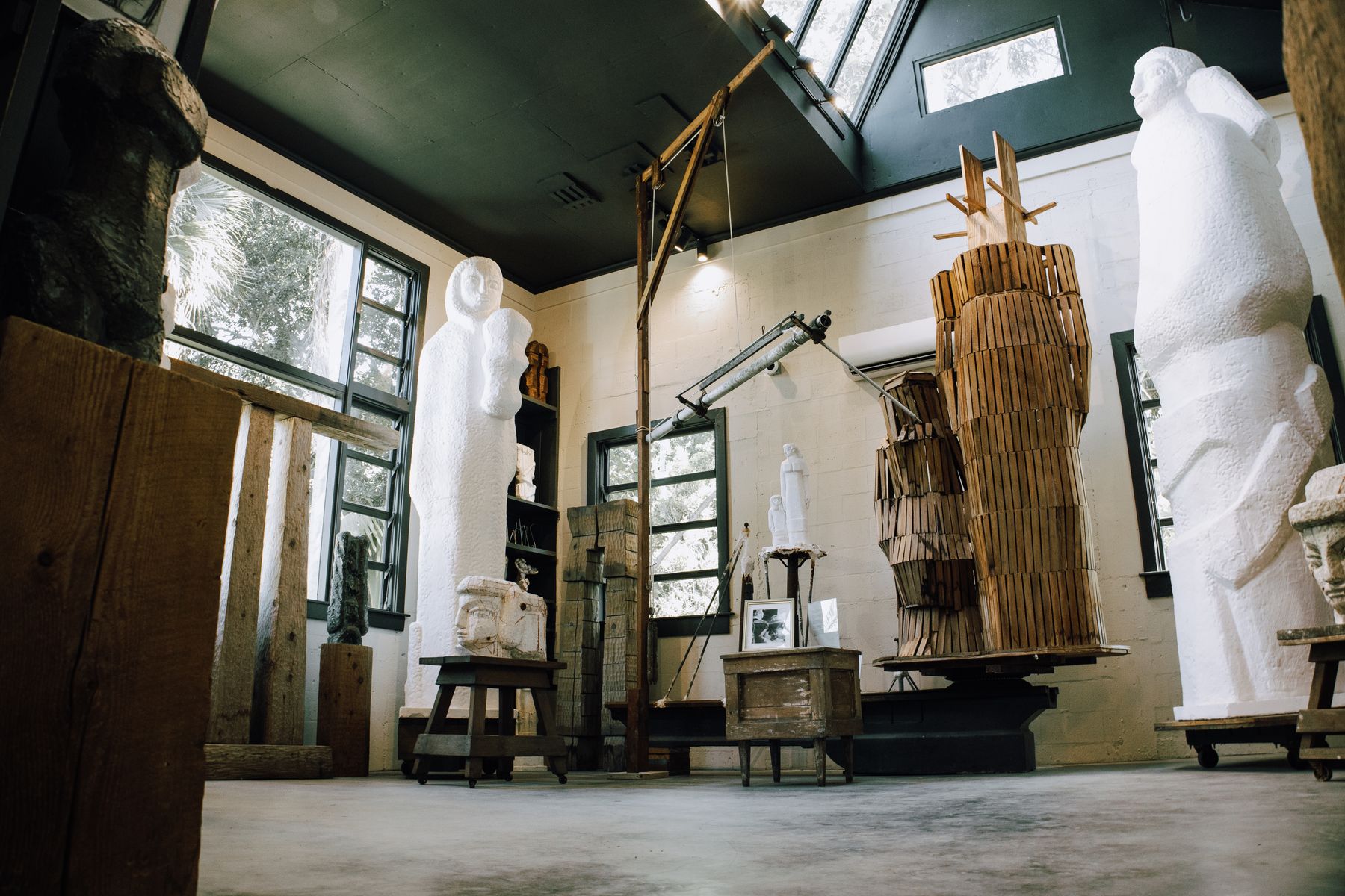 A naturally lit sculpture studio interior filled with large figurative works and timber armatures